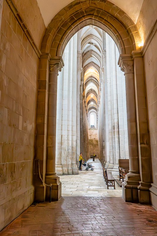 Could not look away_1 Long corridor of gothic stone arches receding into warm amber light, a single distant figure