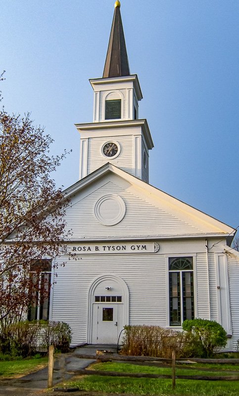 Could not look away_2 White New England clapboard church against a clear blue sky, bare trees, simple and austere