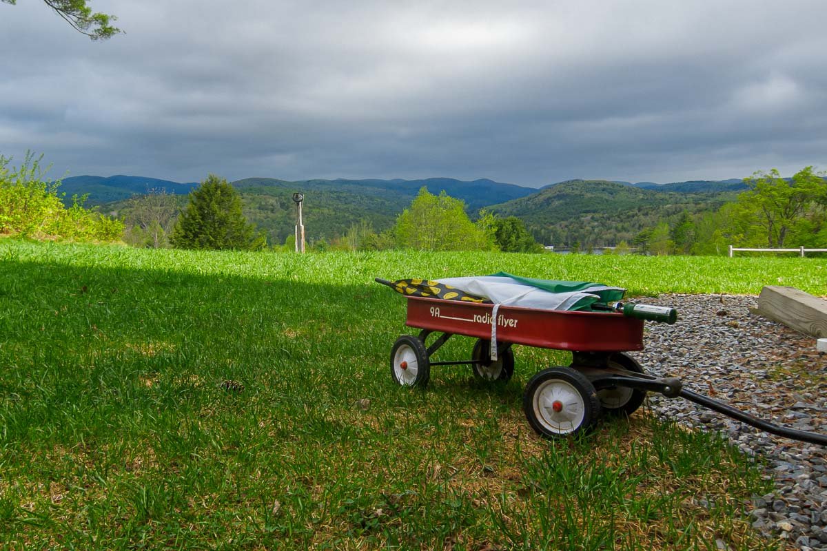 Could not look away_4 A small red wagon sitting alone in a green field under a heavy grey sky