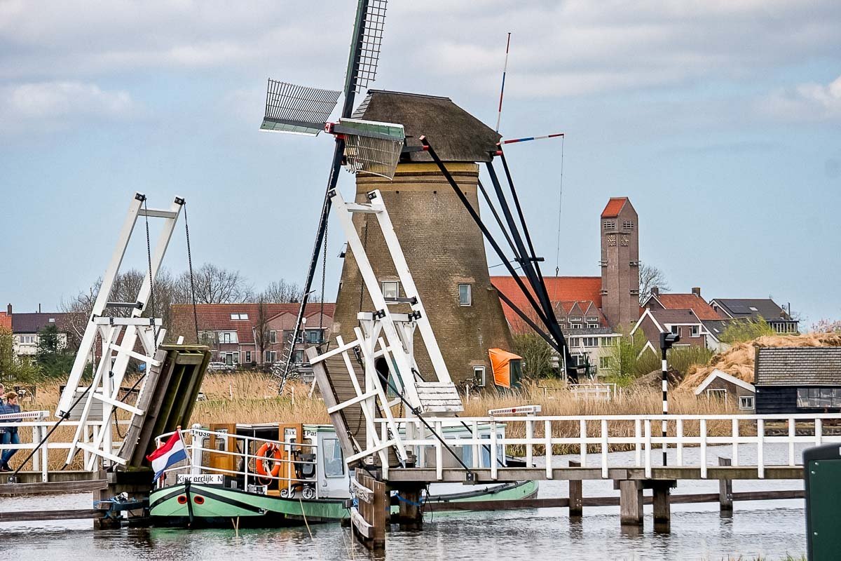 Europe H_12 Working windmill and drawbridge at Kinderdijk UNESCO World Heritage Site, Dutch ferry boat passing through