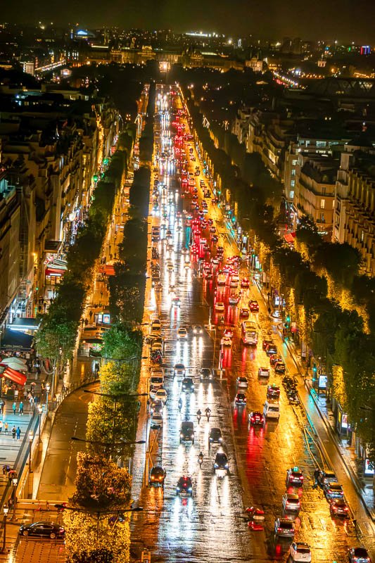 Europe H_17 Aerial view of Champs-Élysées at night in rain, light trails from traffic, wet pavement reflecting gold and red