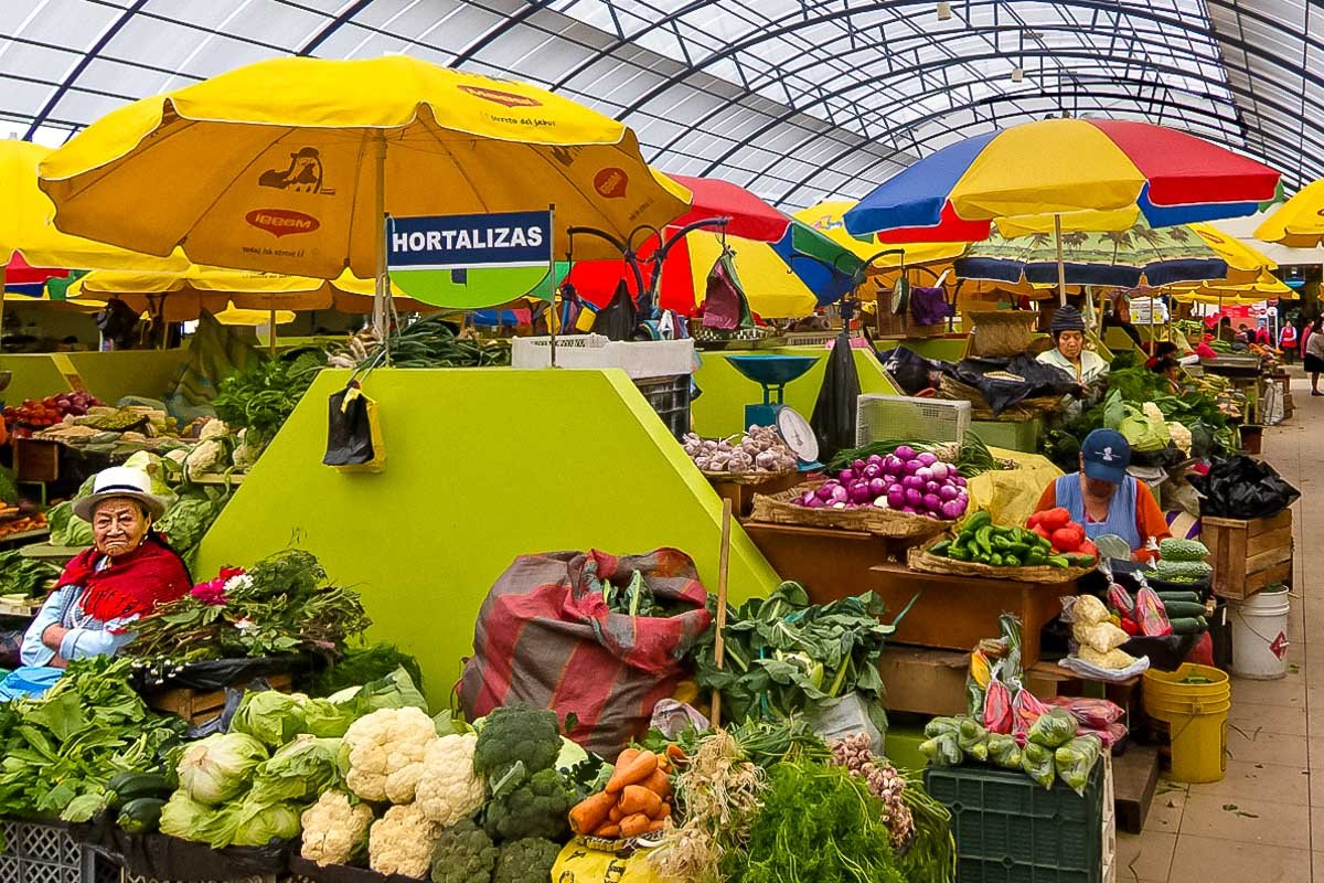 Markets_1 Colorful market stalls with yellow and red umbrellas, fresh produce vendors, shoppers in morning light