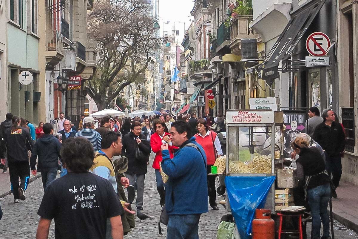 Markets_2 Narrow cobblestone street lined with market stalls, leafless trees, crowds browsing in winter light