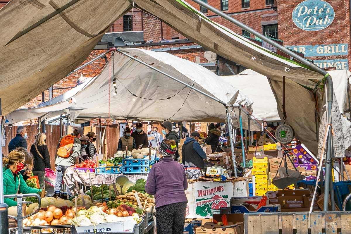 Markets_3 Open-air market with white canvas awnings, vendors displaying fresh vegetables and fruit