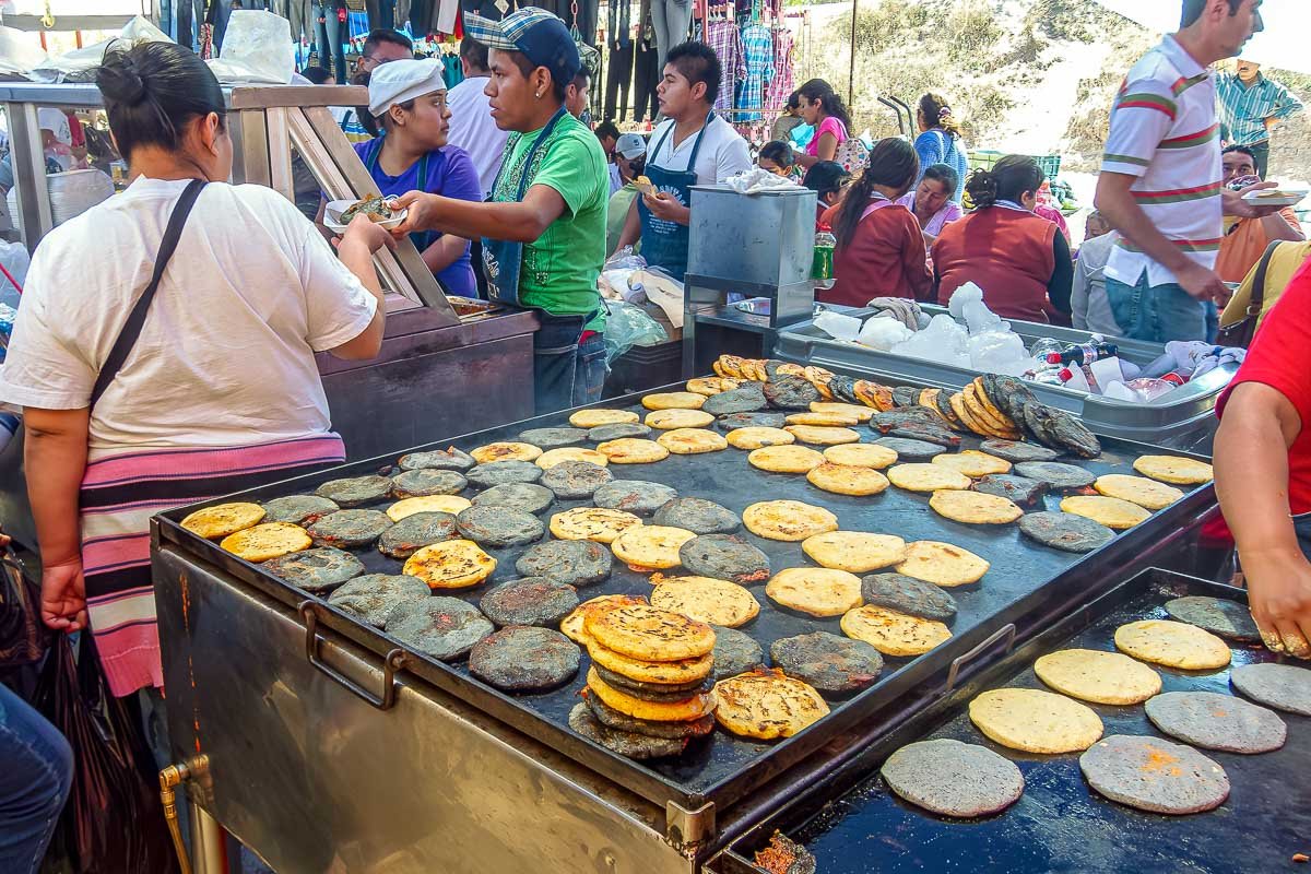 Markets_6 Overhead view of fresh tortillas laid out in rows on a market table, vendor's hands at work