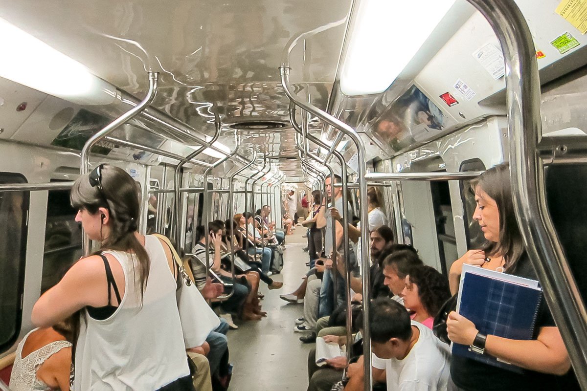 Movement_11 Interior of a crowded metro car, a woman reading in foreground, other passengers around her