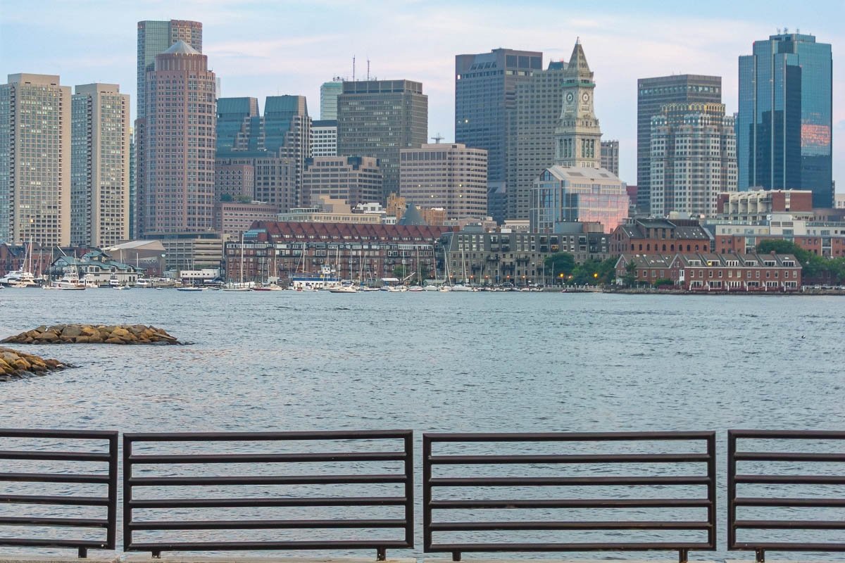 US_Housesit Boston Skyline Boston city skyline viewed from the harbor, modern towers and historic buildings, overcast sky