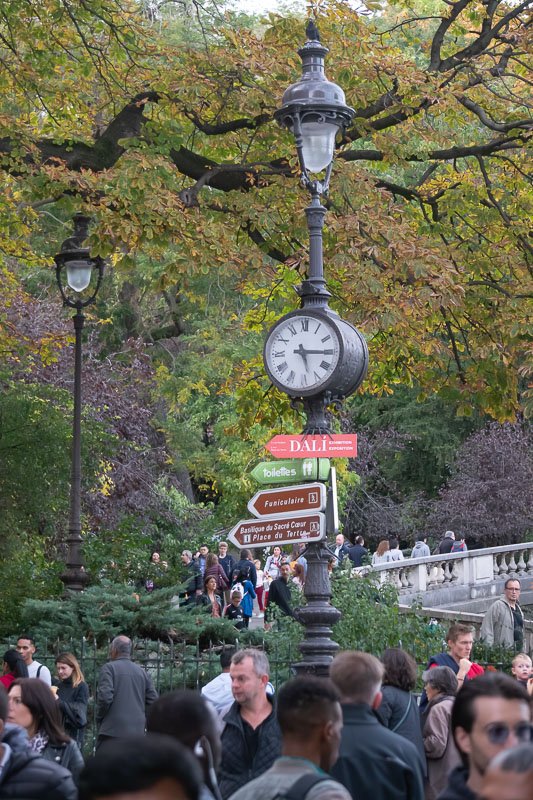 clocks_3 Ornamental green street clock above a dense crowd on a Parisian boulevard, autumn trees