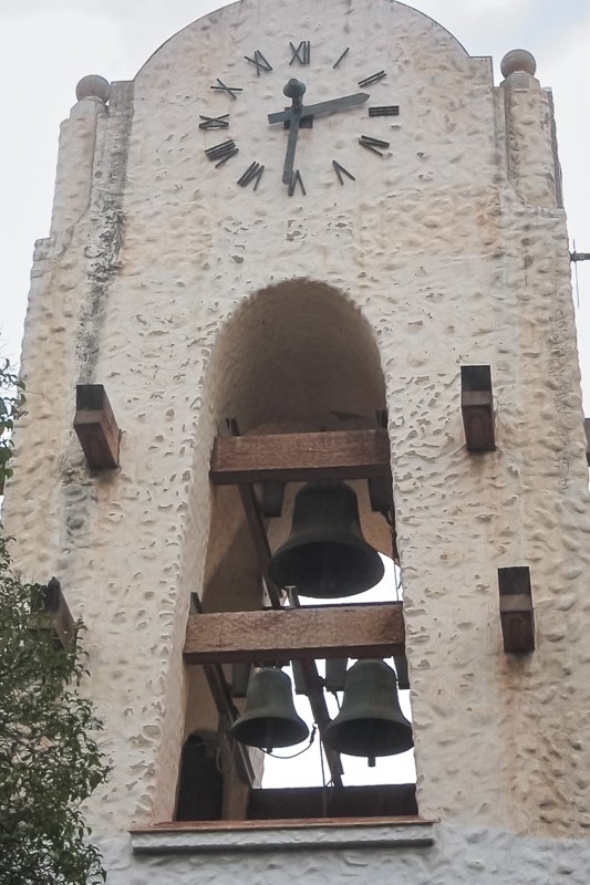 clocks_6 Simple stone bell tower with a small clock face set into an arched niche, bell visible above