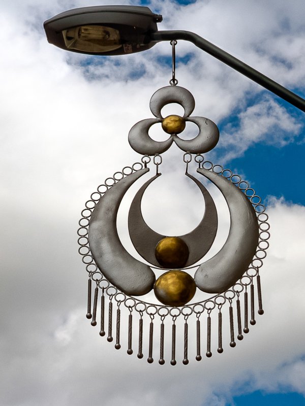 lights Close-up of a decorative lamp fixture shaped like a silver jewelry pendant, Chordeleg Ecuador, blue sky