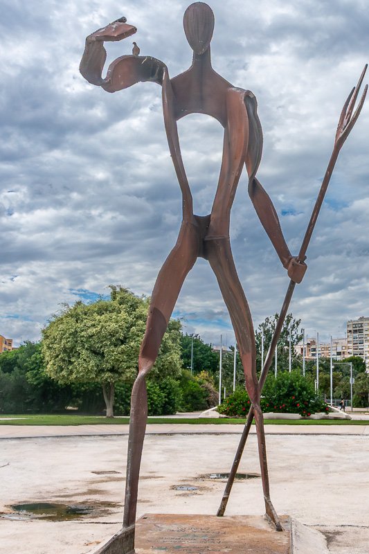 watchers_9 Tall minimal wire sculpture of a striding figure against open sky, spare and kinetic